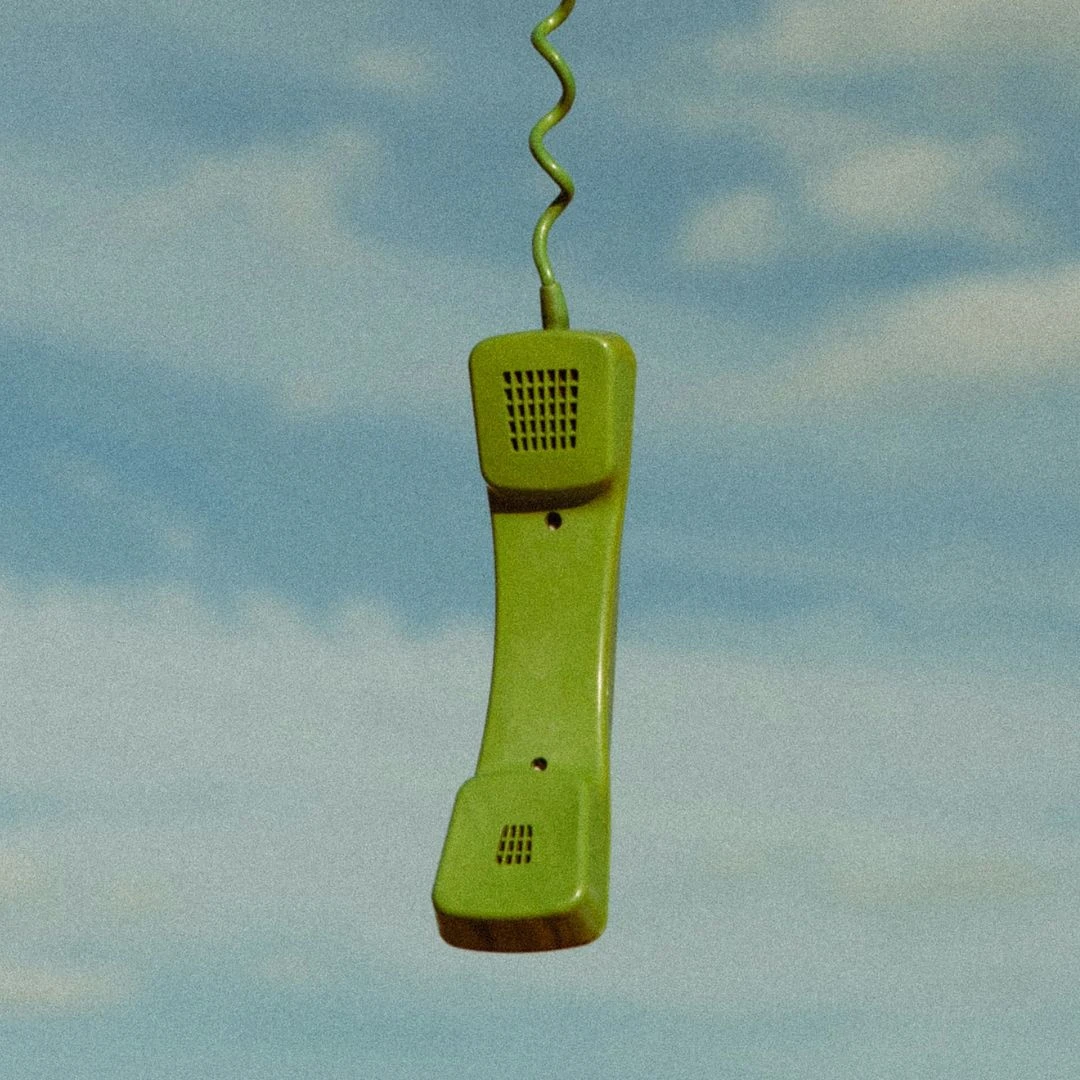 Grüner Telefonhörer vor blauem Himmel